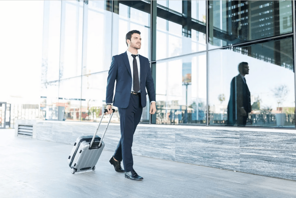 arif patel walking with luggage outside office building