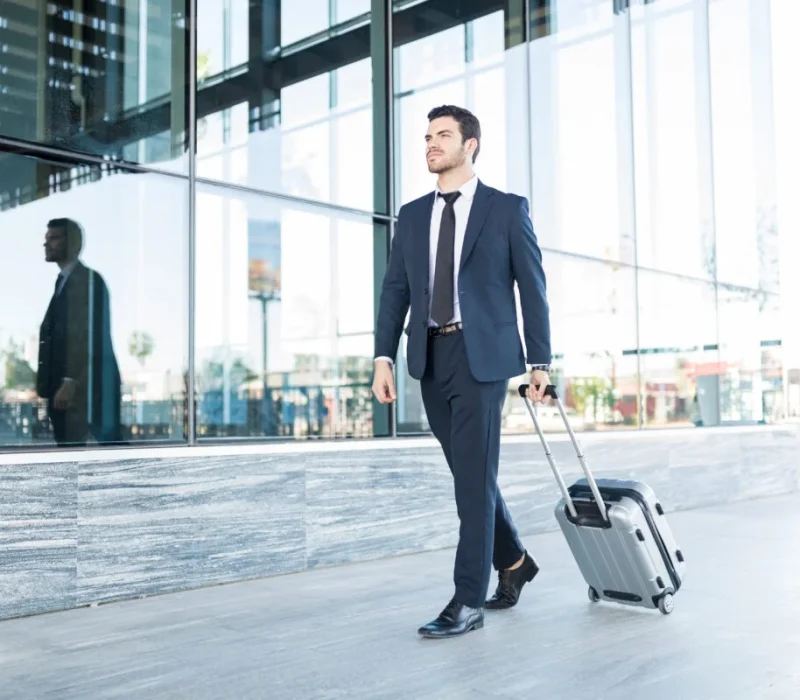 arif patel walking with luggage outside office building